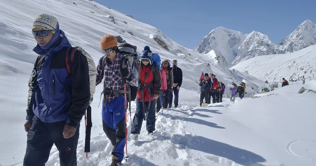 a group of trekkers walking with trekking pole on snow
